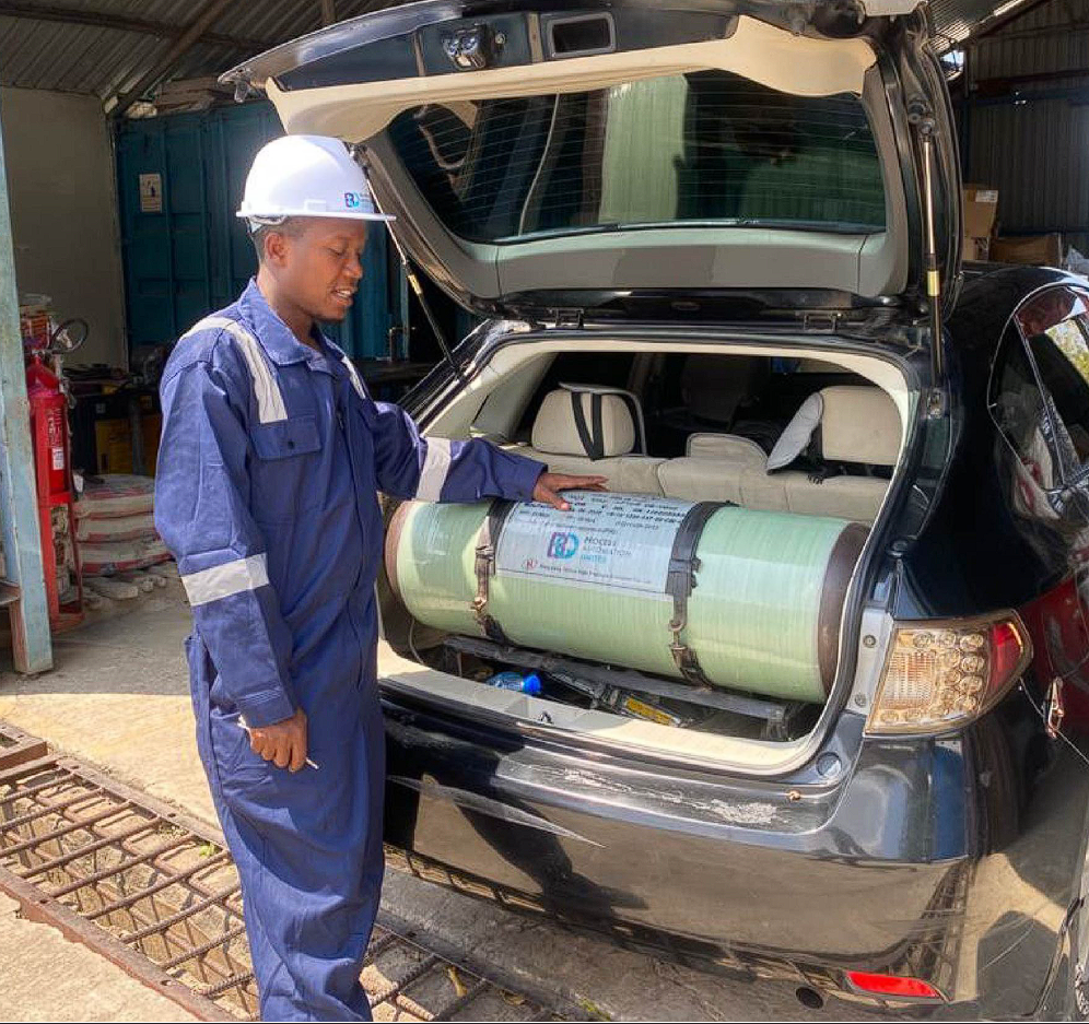 BQ technician showing a CNG cylinder fitted in a vehicle boot after conversion
