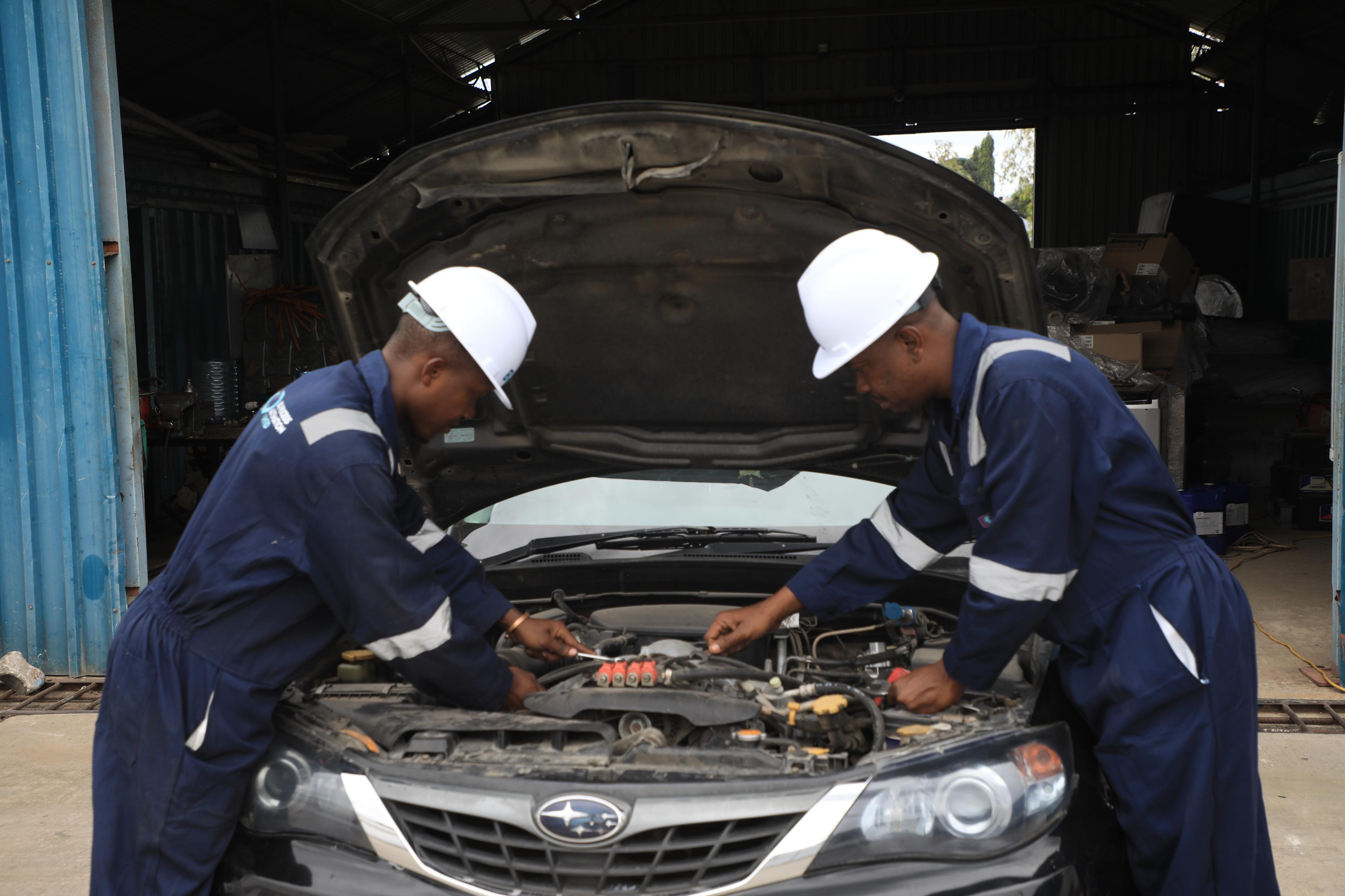 BQ supervisor inspecting a CNG cylinder installed in a vehicle boot